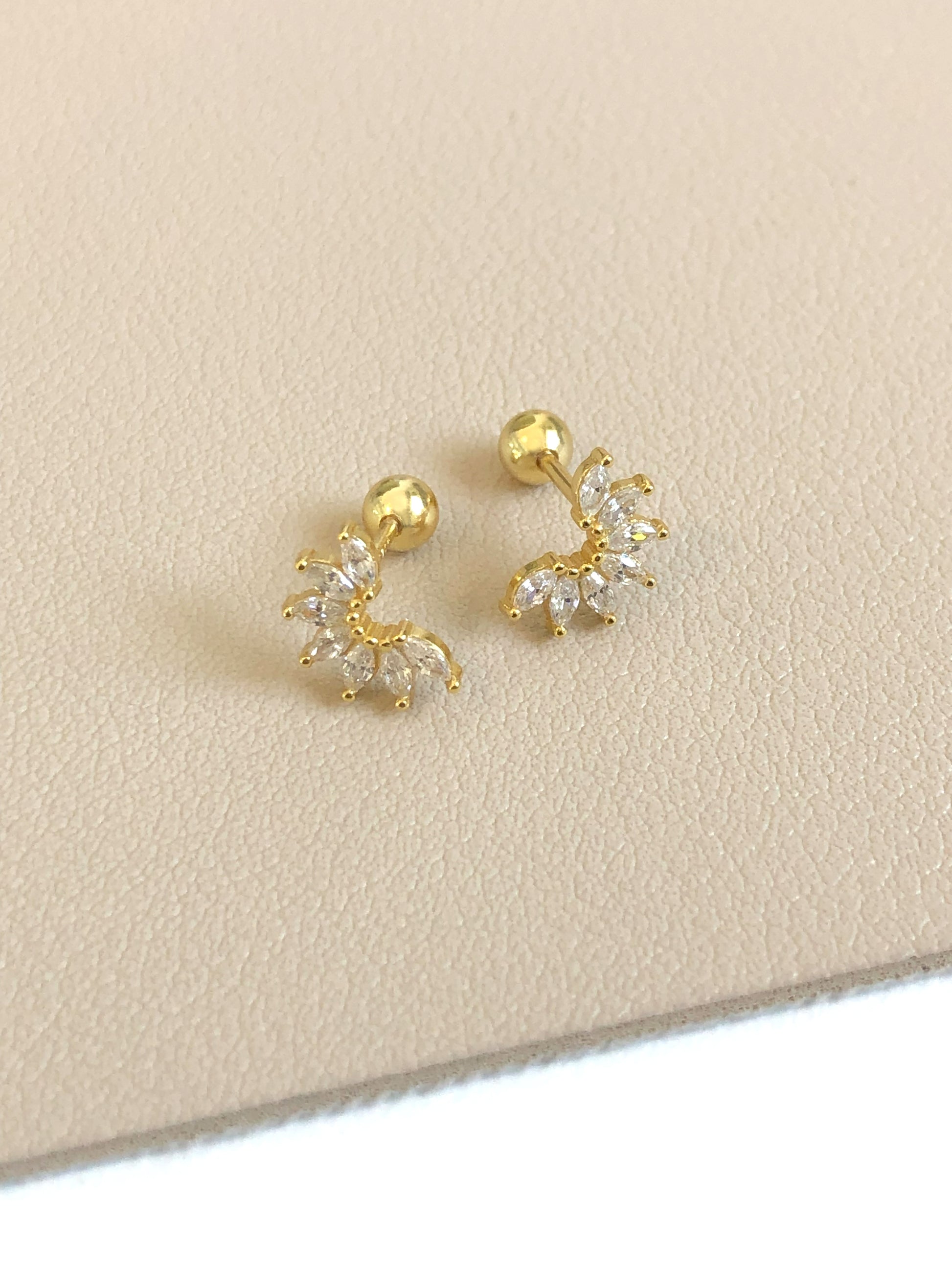 Winter Stud Earrings displayed on beige surface, showing cubic zirconia frost petal design and 18K gold finish.