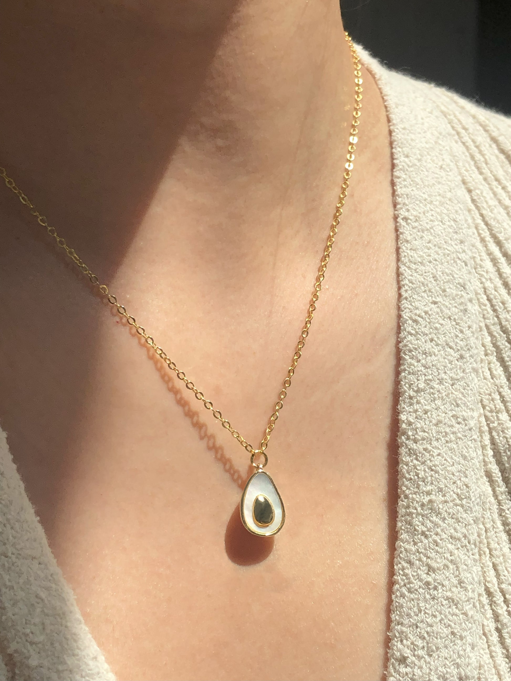 FAVES Avocado Necklace on model – 18K gold plated brass avocado pendant with white enamel and gold pit, minimal whimsical jewelry for everyday wear